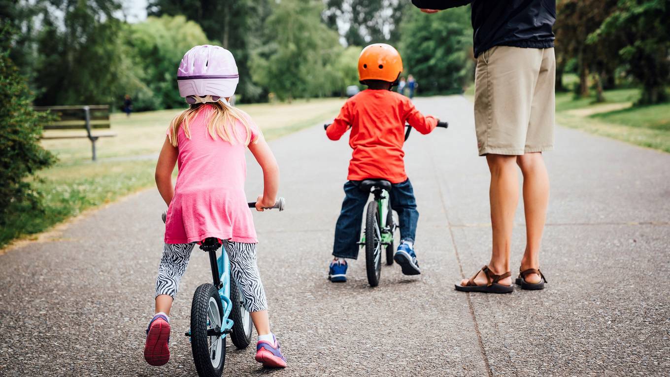 Father watching daughter and son riding bicycles