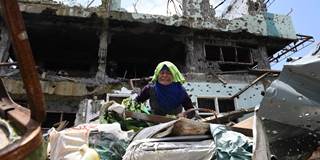 A resident tries to collect salvageable belongings from her destroyed house during a visit to the main battle area in Marawi City