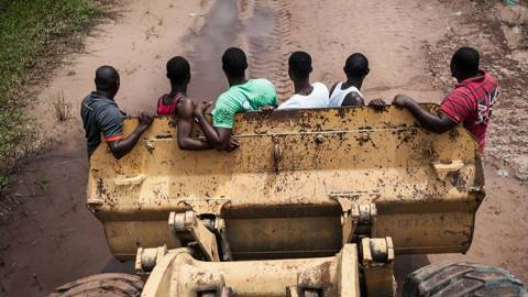 Construction workers ride in the bucket of a bulldozer