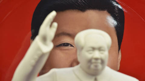Chinese President Xi Jinping is seen behind a statue of late communist leader Mao Zedong