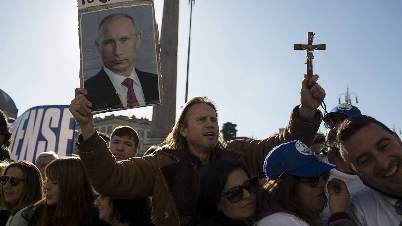 verhofstadt39_ChristianMinelliNurPhotoviaGettyImages_manholdingcrossPutinposter