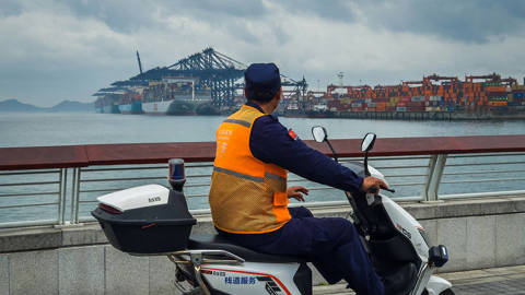 Security Guard drives a scooter by a shipping port in China