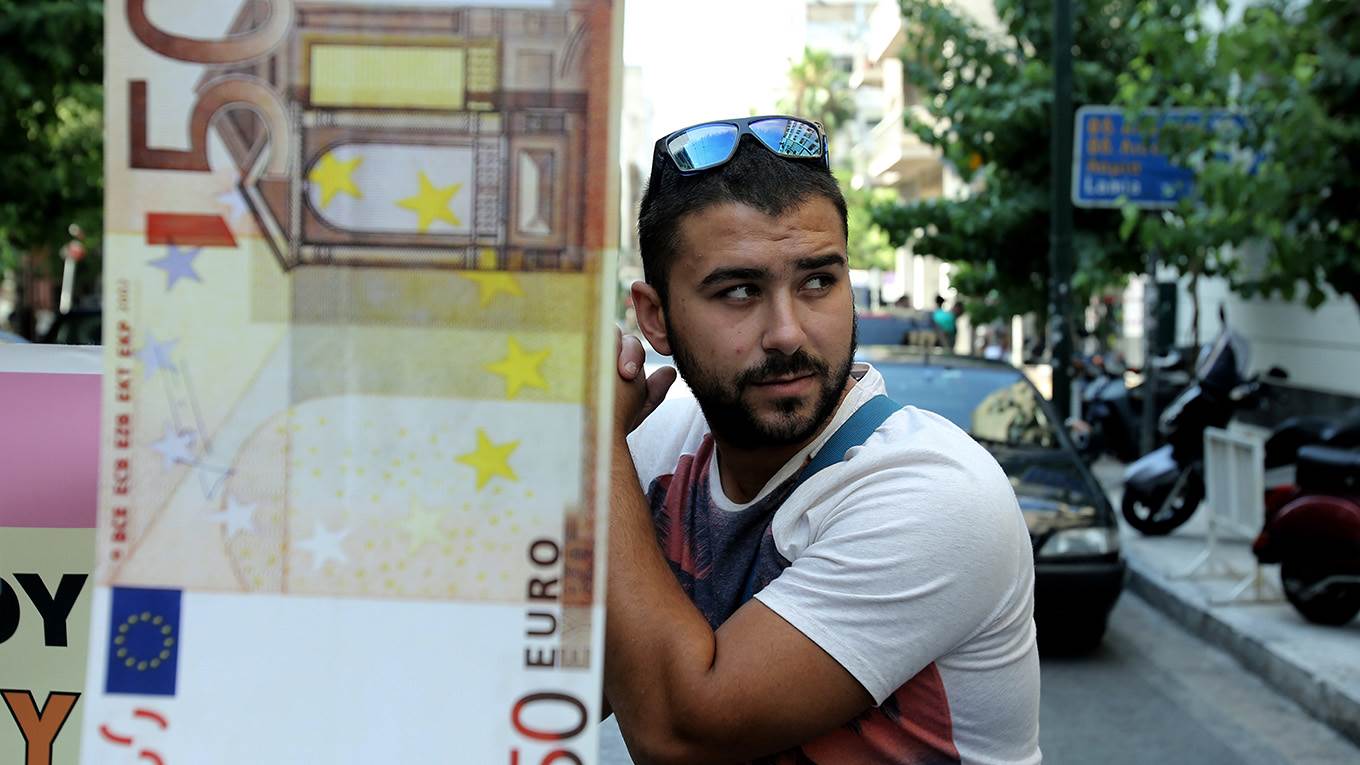 A protestor stand next to a 50 euro note dummy