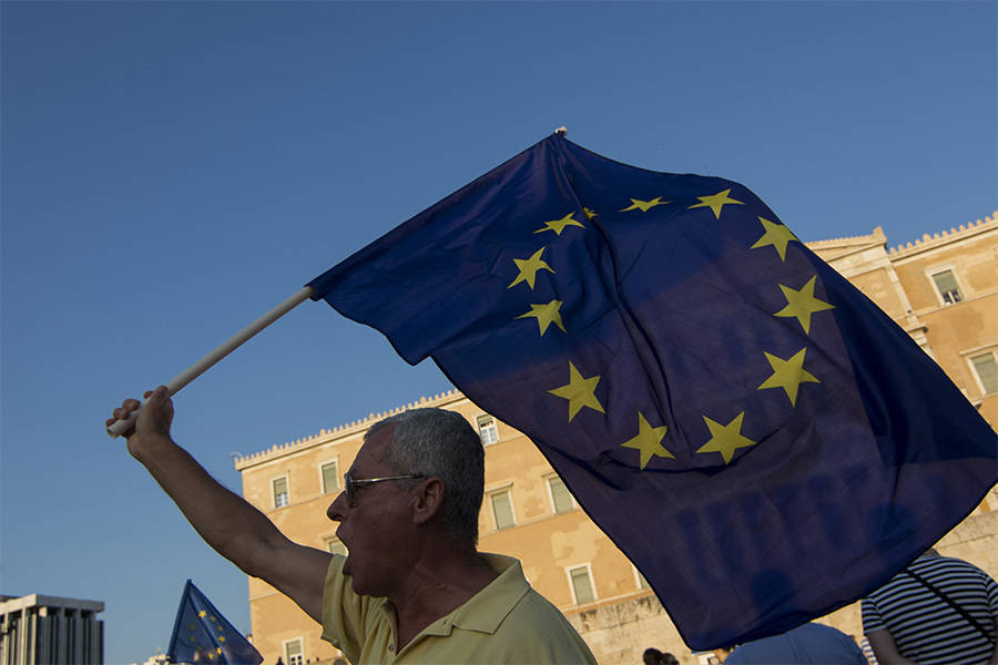 protester with EU flag outside Greek parliament