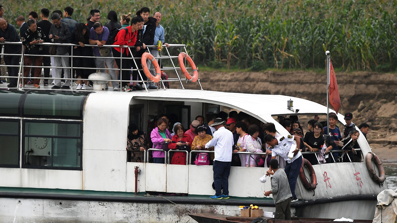 A North Korean man sells items to Chinese tourists