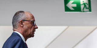 German Chancellor Friedrich Merz walks past an exit sign at CDU headquarters in Berlin.