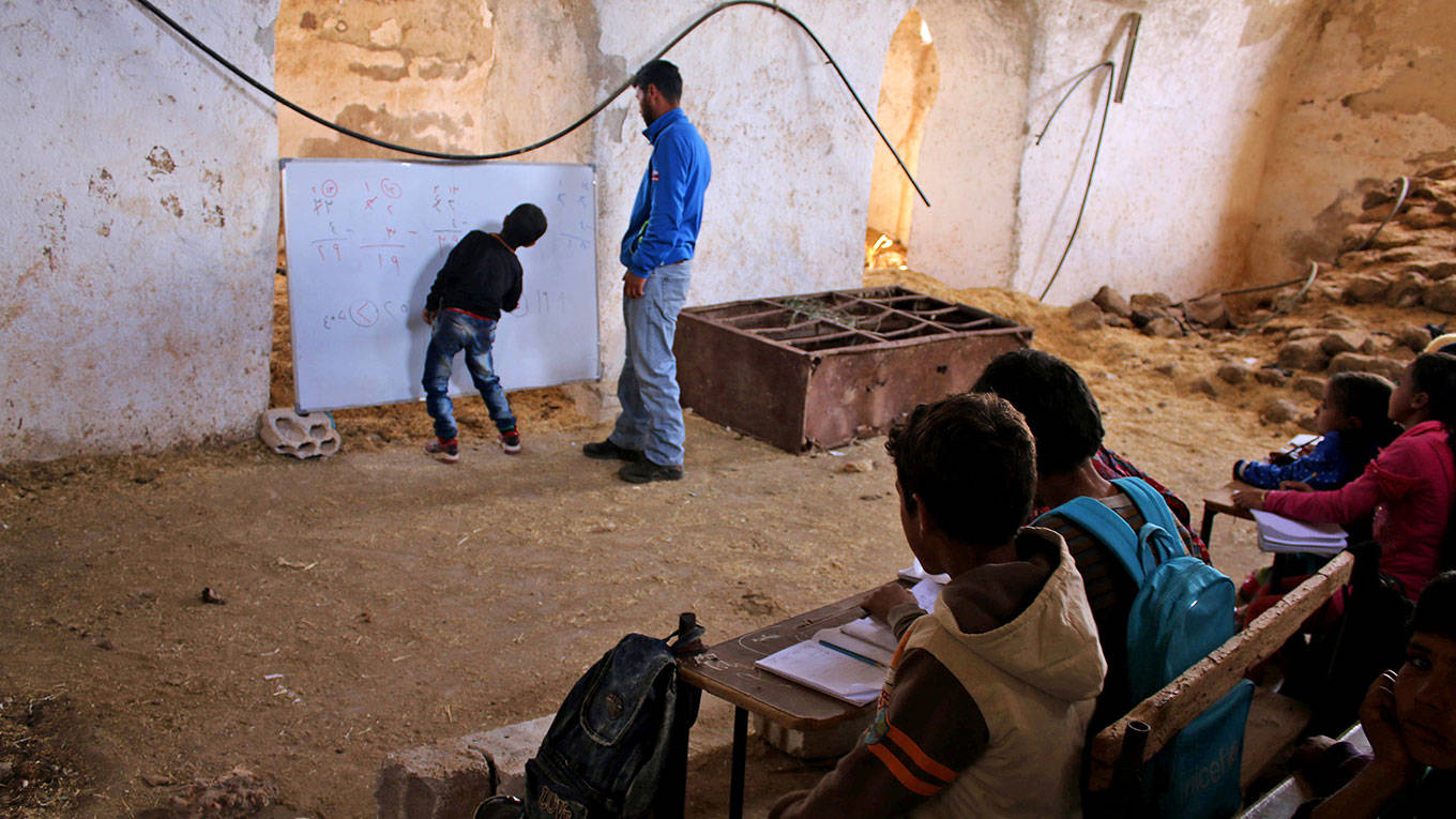 A Syrian boy practices basic arithmetic operations with a teacher