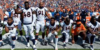 American football players take a knee during the national anthem