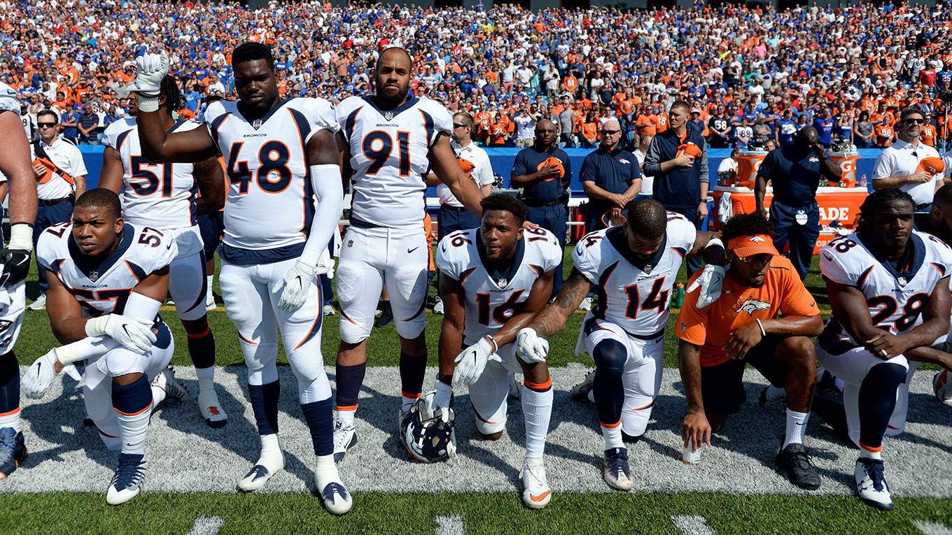 American football players take a knee during the national anthem