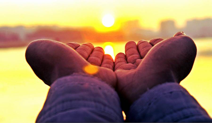 Child's hands imposed with sunset.