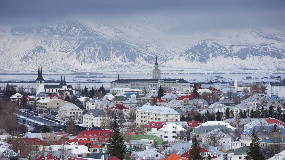 Reykjav&iacute;k, Iceland, with colorful rooftops and snow-covered mountains in the background.