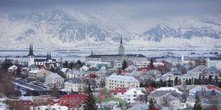 Reykjav&iacute;k, Iceland, with colorful rooftops and snow-covered mountains in the background.