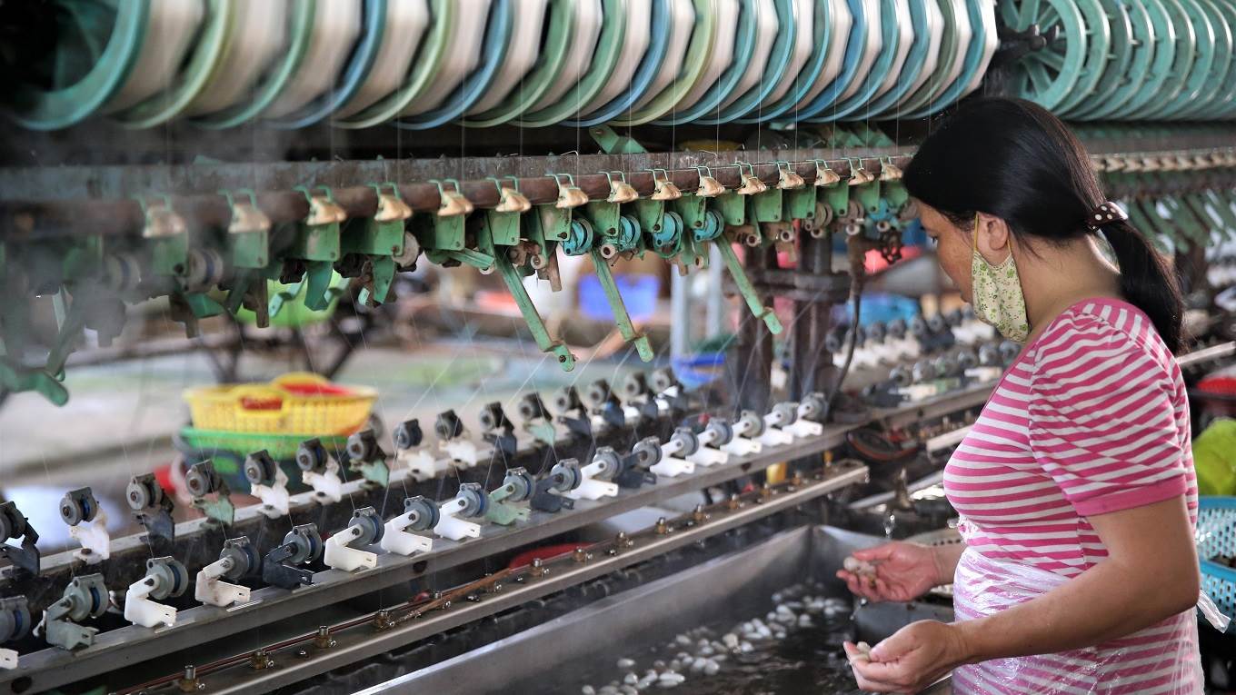 Woman working on silk spinning machine