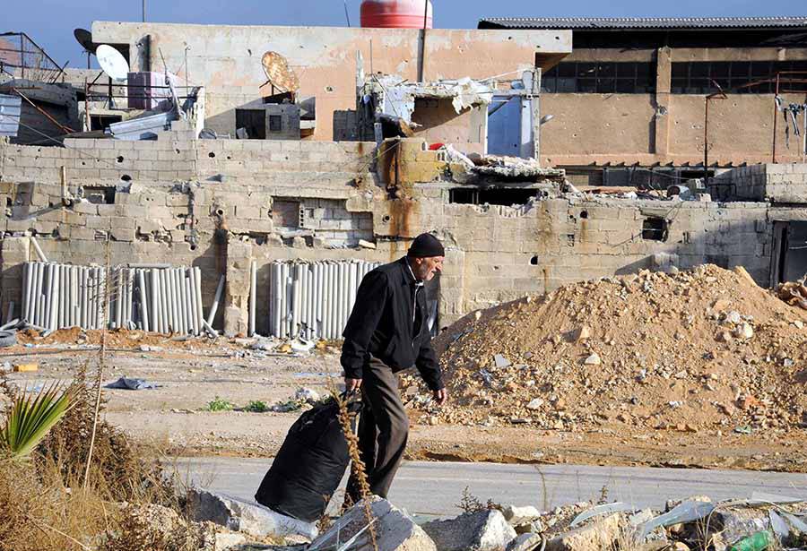 Man in demolished neighborhood in Syria