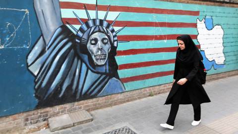 An Iranian woman walks past a mural on the wall of the former US embassy in the Iranian capital Tehran 