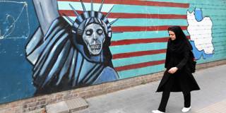An Iranian woman walks past a mural on the wall of the former US embassy in the Iranian capital Tehran 