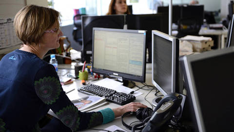 Female journalist of AFP political departement, Karine Perret works on at her computer at the global news agency Agence France-Presse (AFP) in Paris.