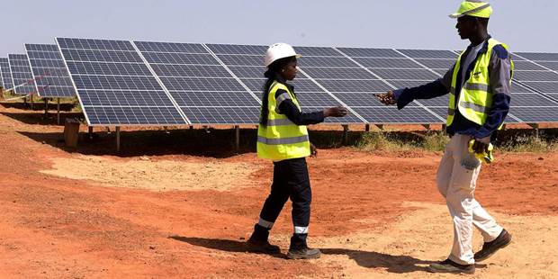 Technicians walk through solar panels