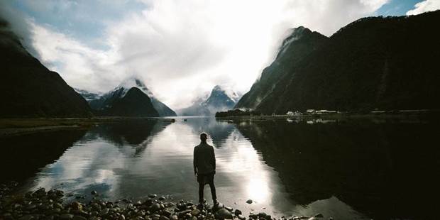 Man standing at lake in mountains.