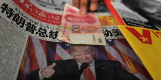  A vendor picks up a 100 yuan note above a newspaper featuring a photo of US president Donald Trump
