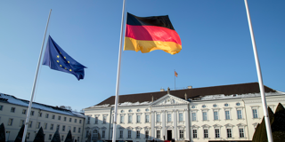 A German and a EU flag fly at half mast in front of the Bellevue presidential palace in Berlin