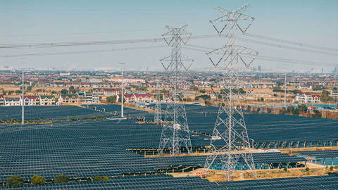 Aerial view of solar panels and high voltage electricity tower composing smart grid.