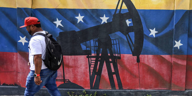 Man walks by a mural of an oil pump on the Venezuelan flag.