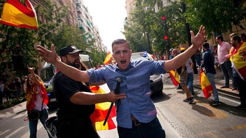 A Spanish policeman tries to avoid clashes between people holding Spanish flags