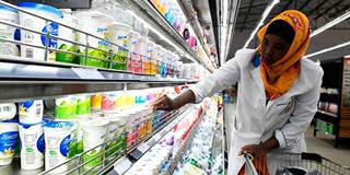 A shop assistant fills the shelves with dairy products 