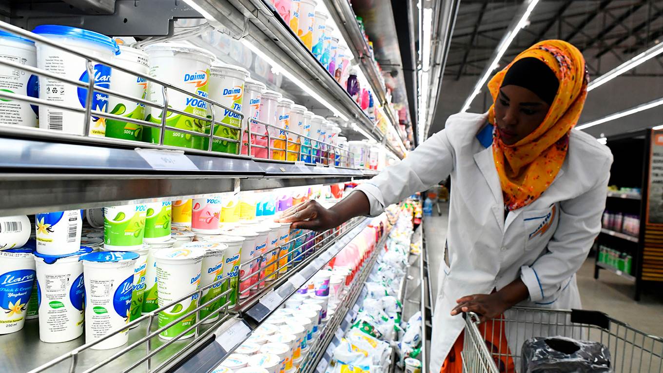 A shop assistant fills the shelves with dairy products