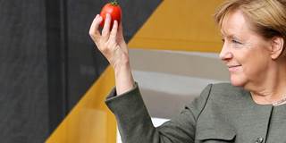 Angela Merket holds up a tomato
