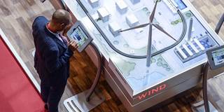 A visitor uses a tablet dispalyed past the model of a smart city 