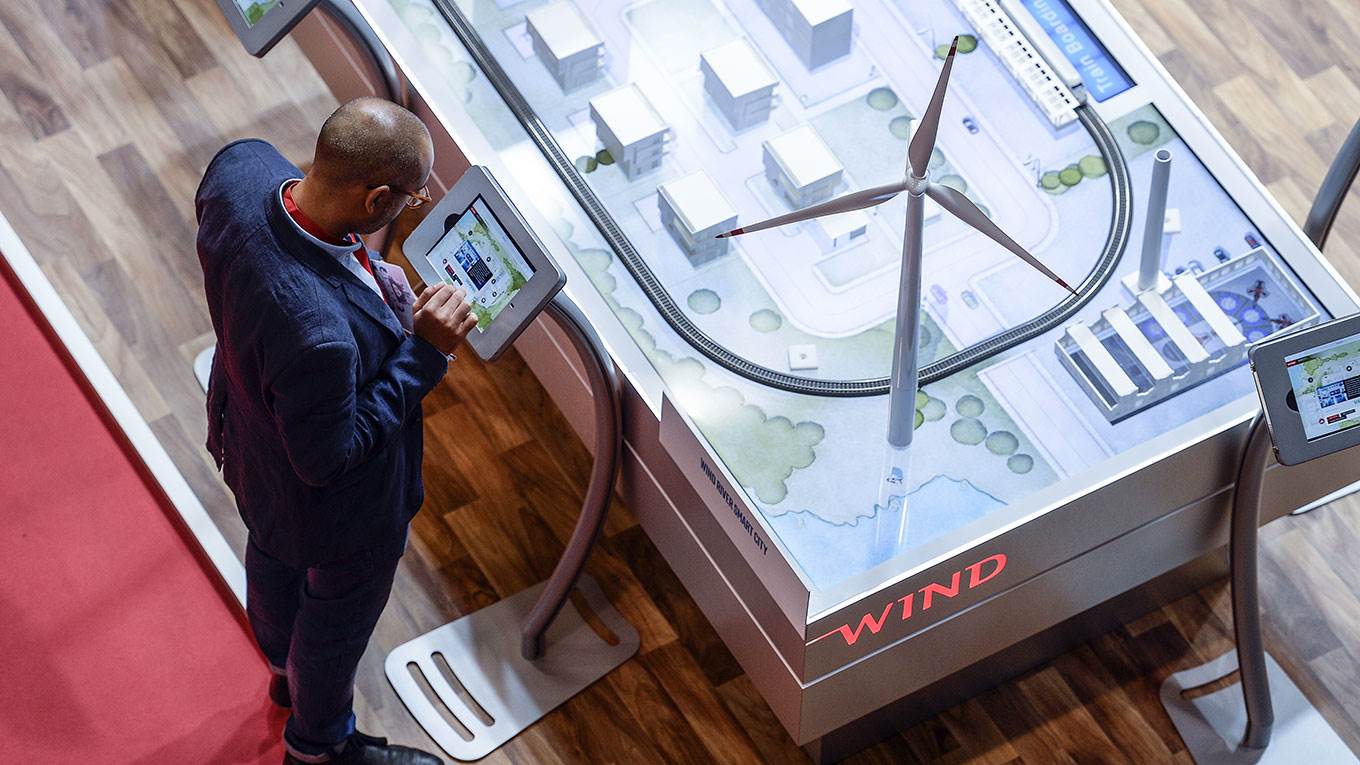 A visitor uses a tablet dispalyed past the model of a smart city