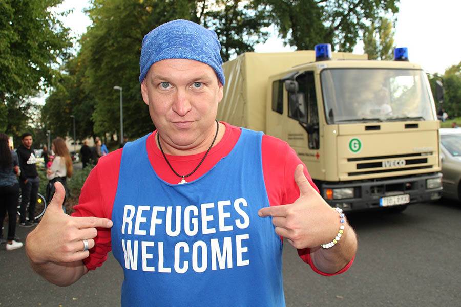 German male with 'Refugees Welcome' shirt on.