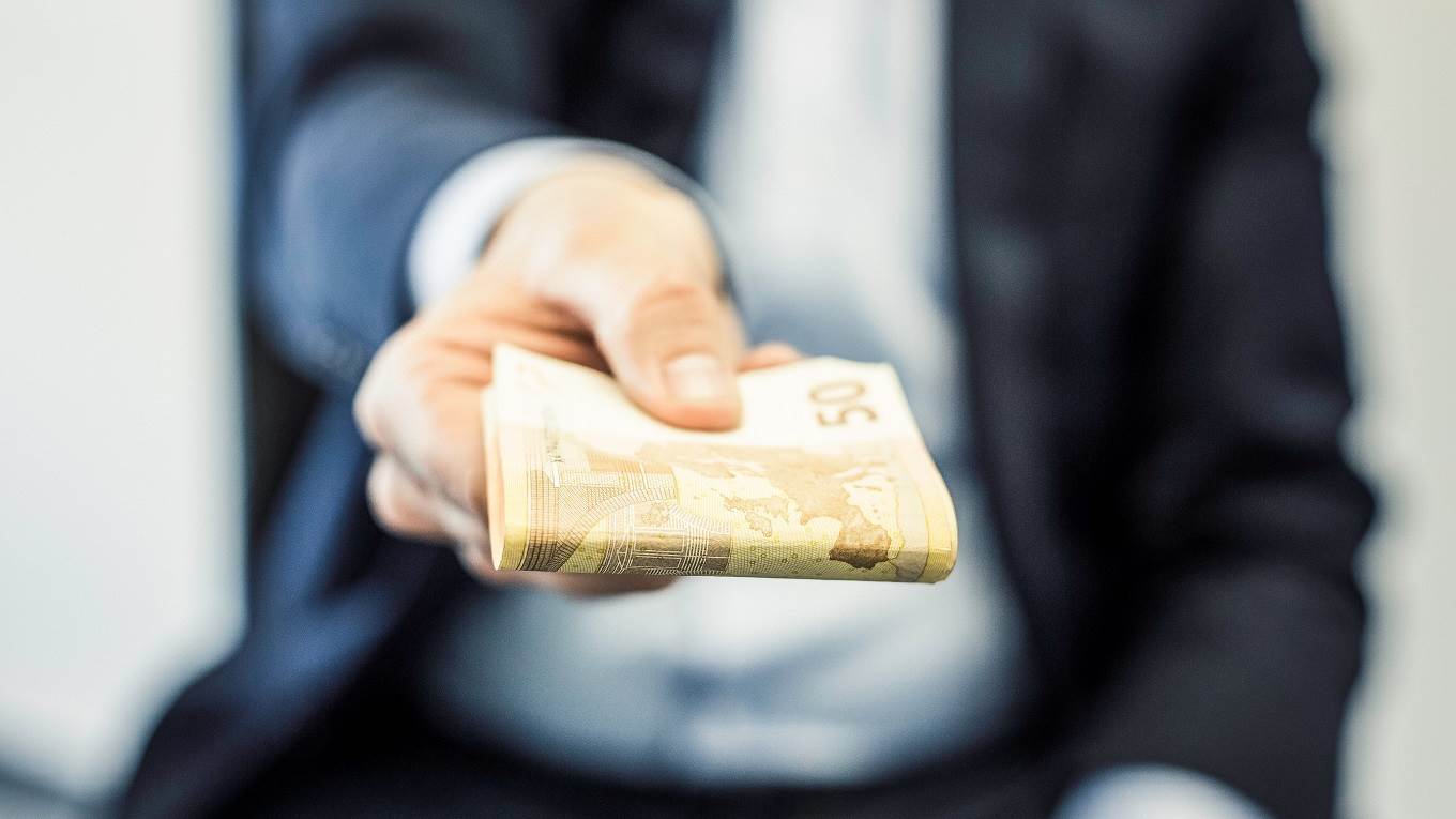 Businessmans handing folded fifty euro notes