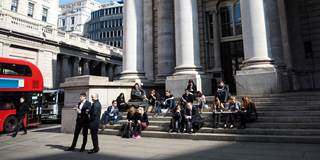 People sit in the sun outside the the Royal Exchange in the City of London