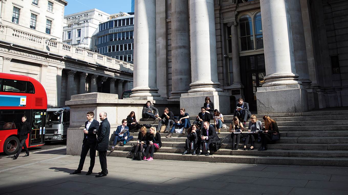 People sit in the sun outside the the Royal Exchange in the City of London