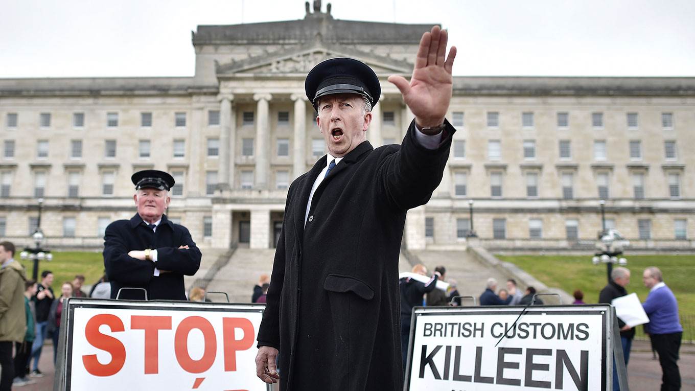 Two men dressed as customs officers take part in a protest