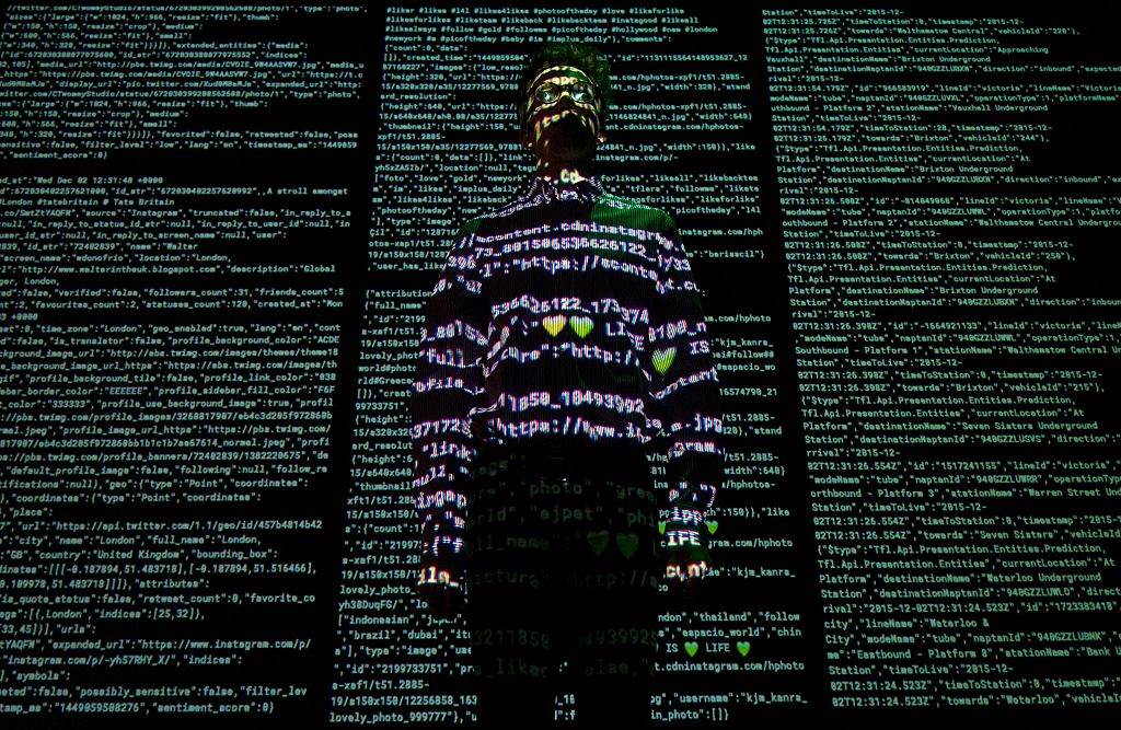 A member of staff poses for a photograph in a projection of live data feeds taken from Twitter, Instagram and Transport for London, as he stands in the 'London Situation Room,' a n artwork created in collaboration with Future Cities Catapult & Tekja, during a photocall to promote the Big Bang Data exhibition at Somerset House in London on December 2, 2015.