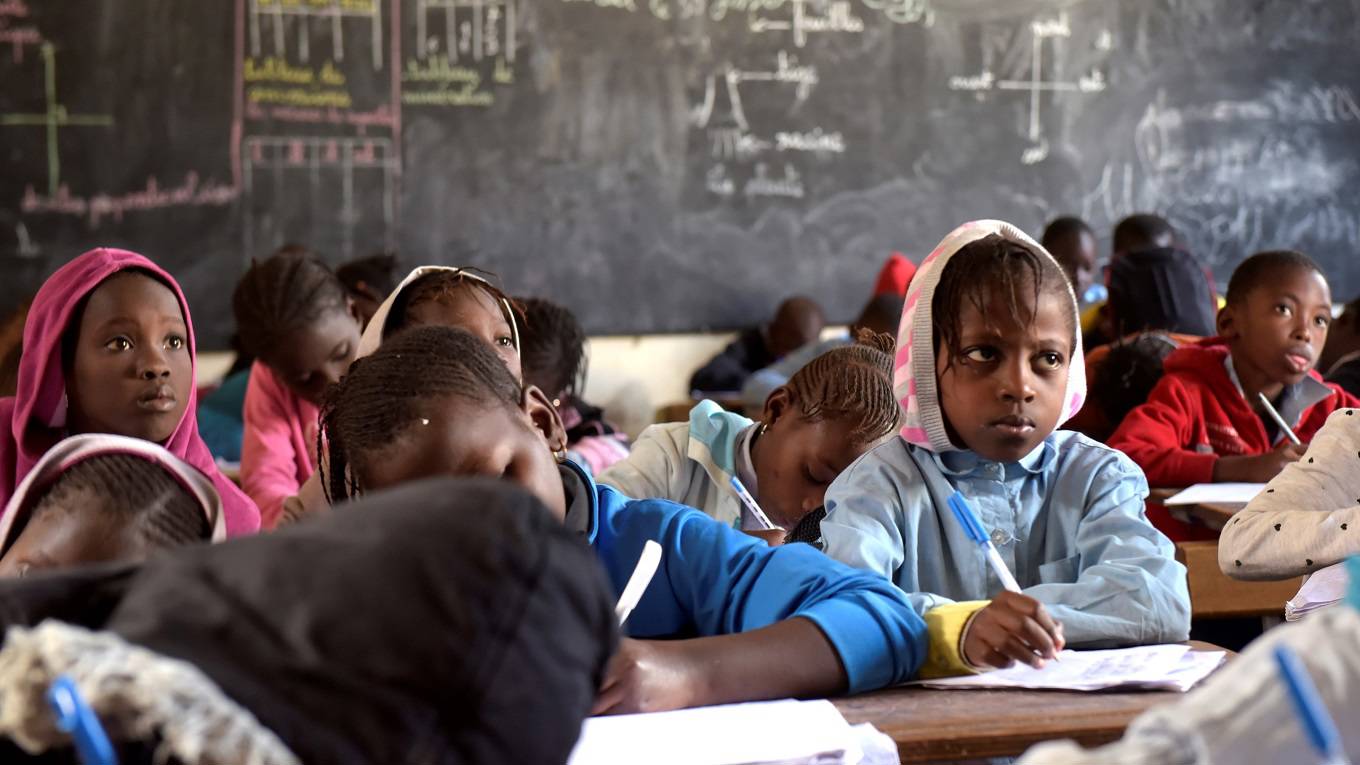 Pupils write on their notebook as they attend class at a primary school in Pikine