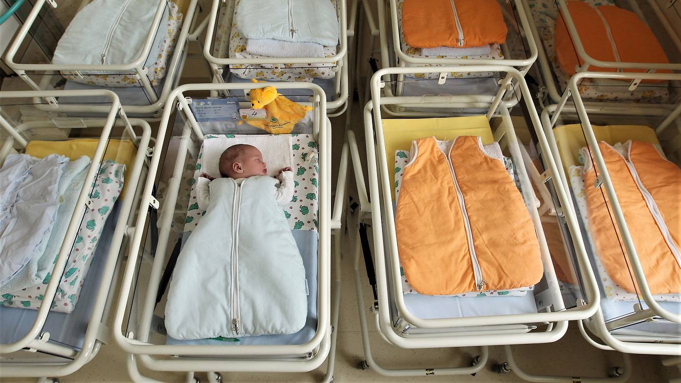 A 4-day-old newborn baby, who has been placed among empty baby beds