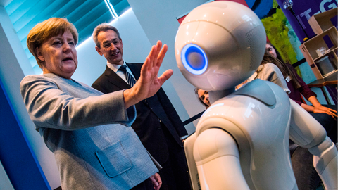 Angela Merkel gestures towards an interactive robot 