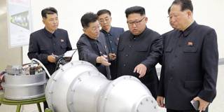 North Korean leader Kim Jong-Un looking at a metal casing with two bulges at an undisclosed location