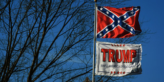 Two flags flying side by side along the Lincoln Highway in Chester, West Virginia: a Confederate flag and a Trump “MAGA” flag.