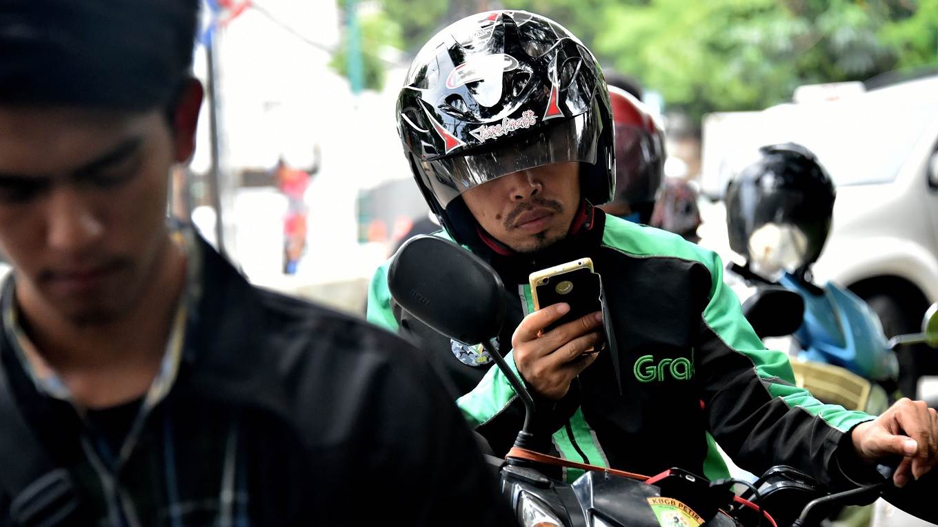 A GrabBike rider uses his mobile phone