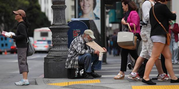 A homeless man holds a sign as he panhandles for spare change 