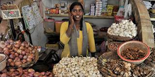 An Indian woman talks on her mobile phone at a vegetable market