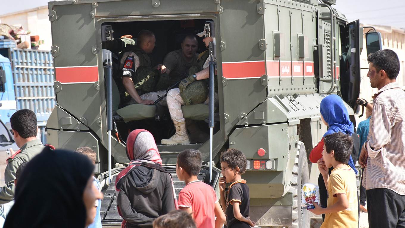 Children gather next to members of the Russian military police in Syria