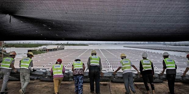 Chinese workers push a section of panels into the water 