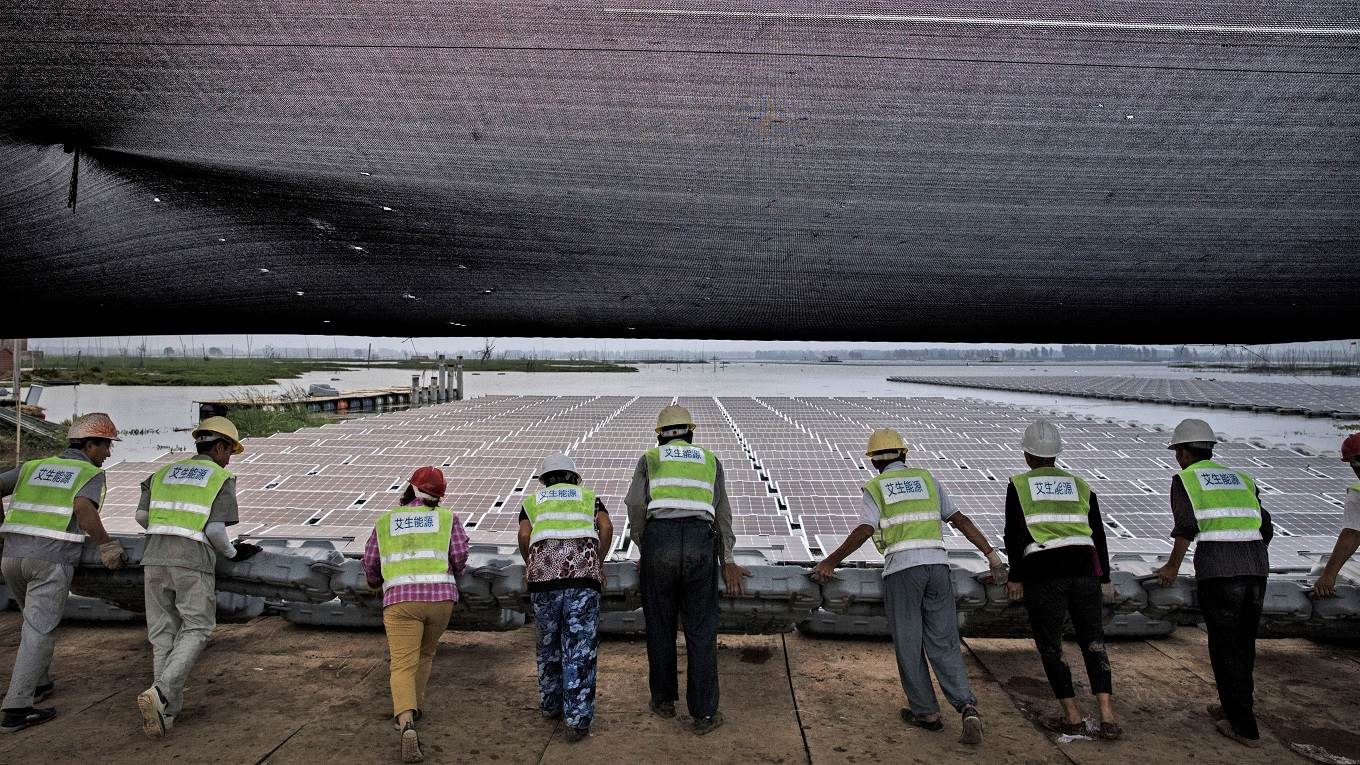 Chinese workers push a section of panels into the water